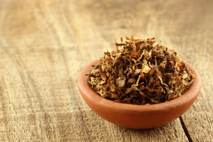 Close-up of tobacco in a small brown bowl on a wooden table